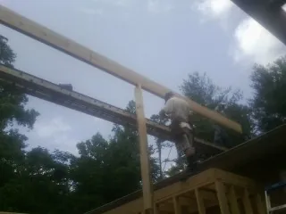 Carpenter setting a ridge beam over a new addition frame — Ice Dam Removal by Roofing Brothers in Iola