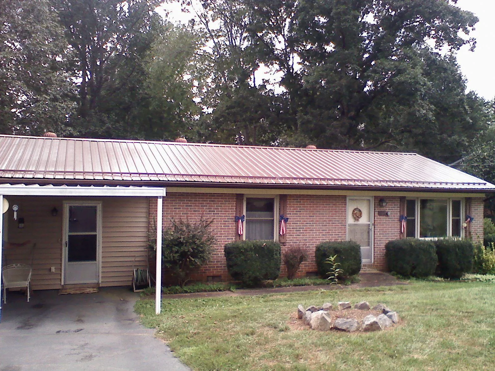 Bronze metal roof and carport on a brick ranch home — Roof Repair work by our crew in Iola