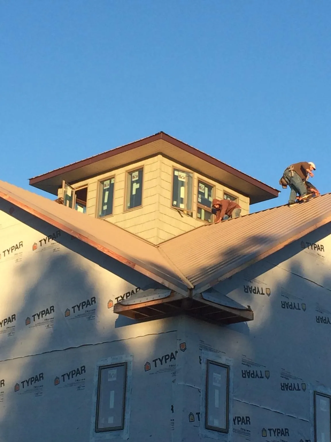 Roofers working around a rooftop cupola on a new metal roof at sunset — Roof Waterproofing in Iola by Roofing Brothers